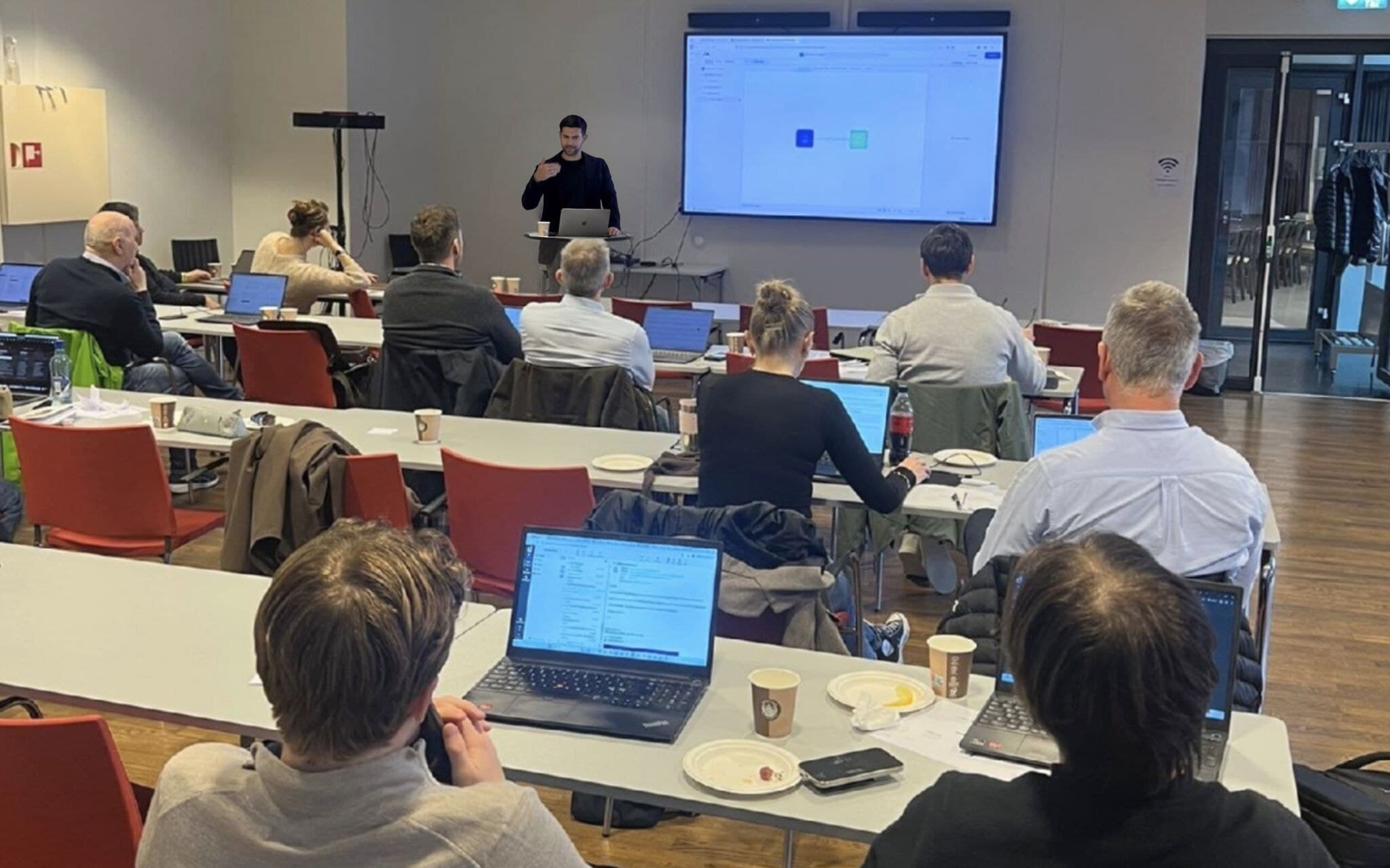 Francisco presenting a workflow diagram to a room of participants with laptops